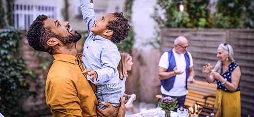 Father lifting child to fairy lights